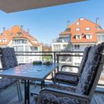 Terrasse mit Tisch und Stühlen, Blick auf Wohnhäuser mit roten Dächern.