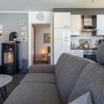 Wohnbereich mit Sofa, Küche und Kaminofen