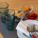 Tisch mit Gläsern, Käse, Crackern und Tomaten auf Untertasse mit Besteck.