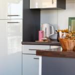 Küche mit weißen Schränken, Kaffeekanne und Korb mit Früchten.