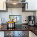 Küche mit Herd, Dunstabzug, Kaffeemaschine und Kochtopf.