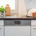 Küche mit Spüle, Waschmaschine und Korb mit Obst.