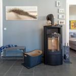 Eingangsbereich mit Kaminofen, Bank und Kunstwerken an der Wand.