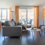 Wohnbereich mit Sofa, Tisch und Balkonansicht.