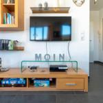 Wohnzimmer mit Fernseher, Holzmöbel und Regalen mit Büchern.