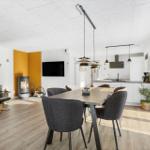 Living and dining area with dining table, kitchen, and wood stove.