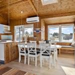 Kitchen with dining area, wooden walls, and windows with view.