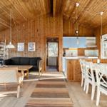 Living and dining area with wooden walls, kitchen island, and dining table.