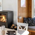 Wood stove with logs and window view. Seat with cushions and wall lamp.