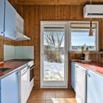 Kitchen with blue cabinets and red worktop. Wooden walls and snow outside.