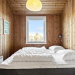 Bedroom with wooden walls, bed, and window with view of trees.