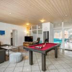 Ein Raum mit Billardtisch, Sofa und Blick auf die Poolanlage.