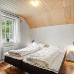 Schlafzimmer mit Doppelbett, Holzdecke und Fenster mit Blick auf Grün.