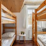 Zwei Holzbetten mit Fenster und kleinem Tisch.
