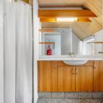 Badezimmer mit Holzregalen, Waschbecken und Dusche unter Dachschrägen.