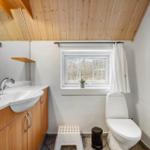 Badezimmer mit Holzdecke, Waschbecken, Toilette und Fenster
