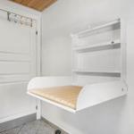 Wandbett mit Matratze und Regal an der Wand. Tür mit bunten Haken.