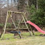 Holzschaukel mit rotem Rutschbahn im Garten
