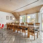 Esszimmer mit Holztisch, Stühlen und großem Fenster. Rote Barhocker und helle Decke.