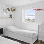 Schlafzimmer mit weißem Bett, Schrank und Fensterblick.
