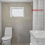 Badezimmer mit Toilette, Waschbecken und Dusche mit Vorhang.