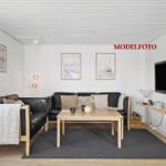 Wohnzimmer mit Sofa, Couchtisch und Wandfernseher.