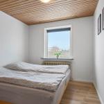 Bedroom with bed, window, and wooden floor.
