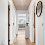 Hallway with wooden floor, white walls, and round mirror on the wall.