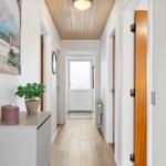 Hallway with wooden floor, white walls, and a door to the outside.