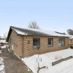 Single-story house with snow-covered roof and stone path.