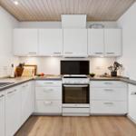 Modern kitchen with white cabinets, dark worktop, and wooden floor.