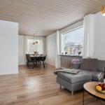 Living and dining area with wooden floor, gray sofa, and dining set.