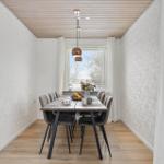 Dining room with long table, chairs, and window with curtains.