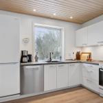 Modern kitchen with white cabinetry, window, and wooden floor.