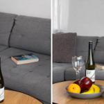 Gray sofa with cushions, table with wine, fruit, and plant.