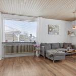 Living room with gray sofa, wooden floor, and large windows.