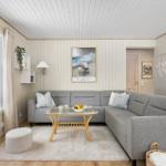 Living room with gray sofa, glass table, and wooden floor. A picture hangs on the wall.