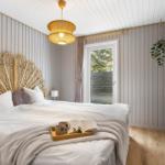 Bedroom with rattan bed and wooden floor. Window with view of garden.