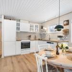 Kitchen with dining area, white cabinets, and wooden floor. Table set with flowers.