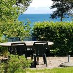 Rundtisch mit Stühlen im Garten mit Blick auf das Meer