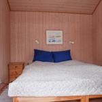 Schlafzimmer mit Holzwand, Bett, Nachttisch und Fenster.