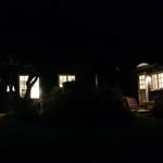 Nachtansicht eines Hauses mit erleuchteten Fenstern und einem Garten