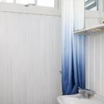 Badezimmer mit Waschbecken, blauer Duschvorhang und Spiegelschrank.