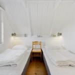 Zwei Betten in einem Dachzimmer mit Holzboden und Fenster.