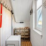 Schlafzimmer mit Dachschräge, Fenster und Schuhschrank. An der Wand hängen Haken und ein Spiegel.