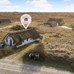 Dorfhaus mit strohgedecktem Dach in hügeliger Landschaft