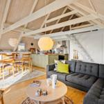 Wohnung mit Essbereich, Küche und Sofa unter Holzdecke.