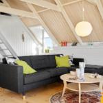 Wohnzimmer mit grafer Sofa, runder Tisch und Holzdecke.