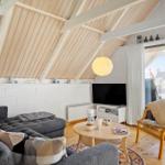 Wohnzimmer mit Sofa, Sessel, TV und Holzboden unter schrägem Dach