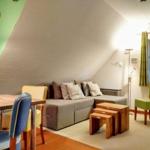 Wohnraum mit Sofa, Tisch und Stühlen unter Dachschrägen.